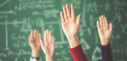 hands raised in front of chalkboard with math equations