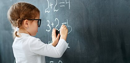 young girl doing math on a chalkboard