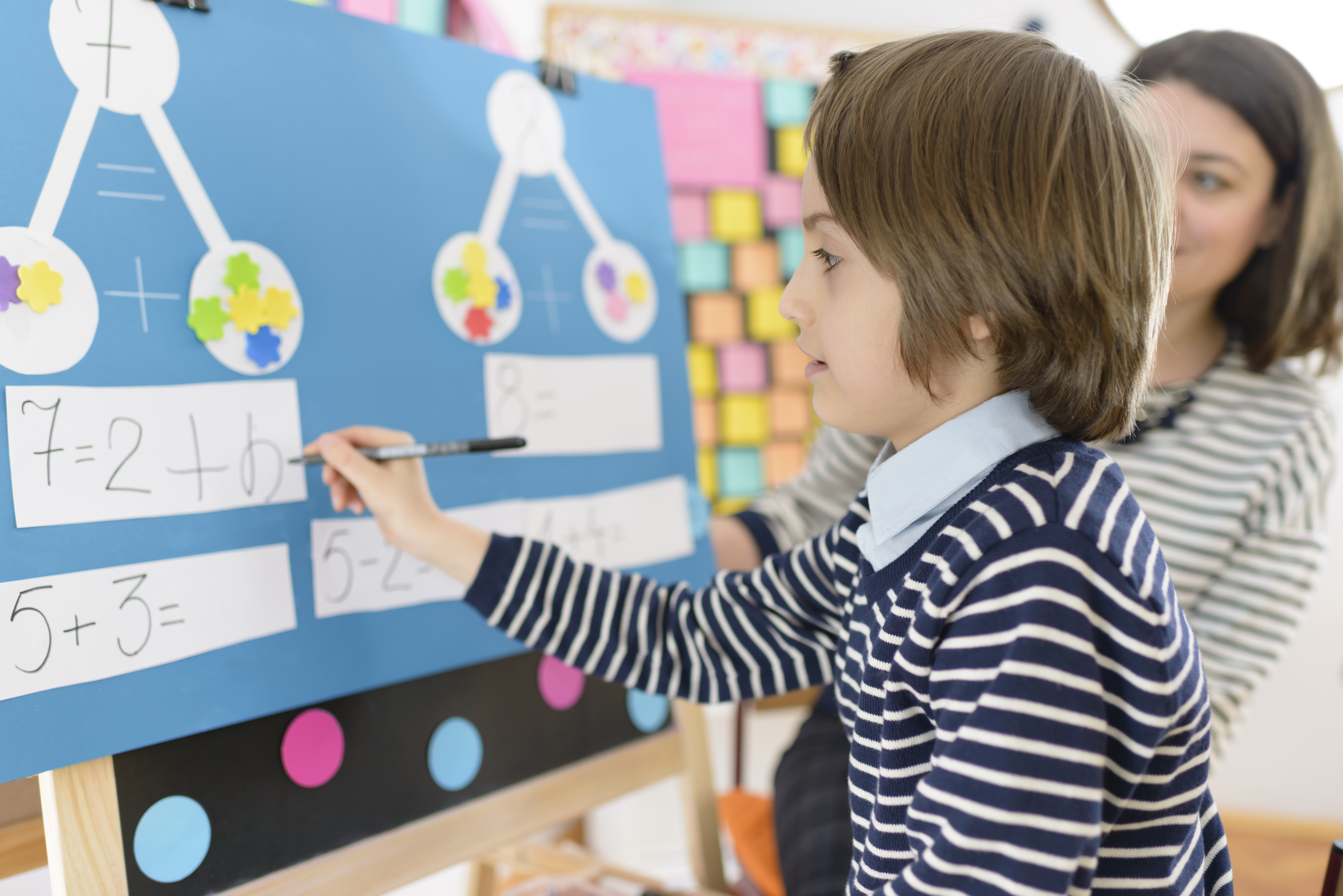 boy doing math problem with teacher