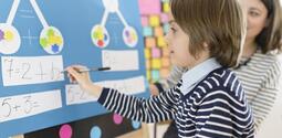 boy doing math problem with teacher